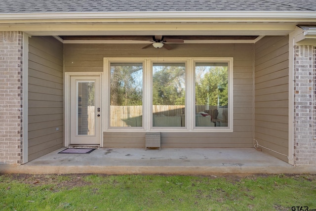 view of exterior entry with ceiling fan and a patio area