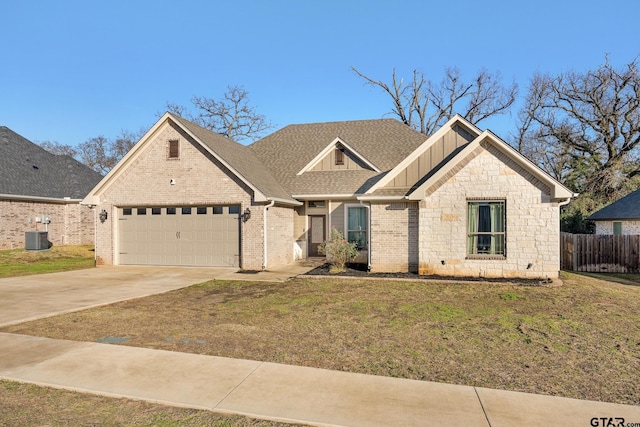 view of front of home featuring a front yard, a garage, and central AC unit