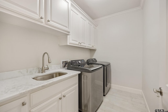 washroom with washing machine and clothes dryer, crown molding, sink, and cabinets