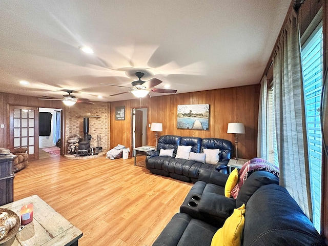 living room with hardwood / wood-style floors, wooden walls, a textured ceiling, and a wood stove