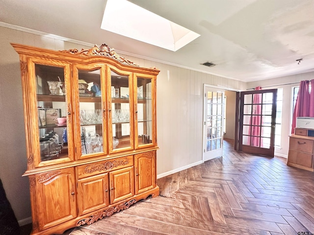 interior space with a skylight, parquet flooring, and ornamental molding