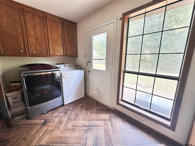 washroom with washer and clothes dryer, dark parquet floors, and cabinets