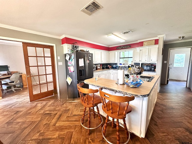 kitchen featuring dark parquet floors, crown molding, stainless steel fridge, and white cabinets