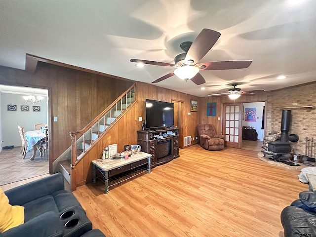 living room with light wood-type flooring, wooden walls, and ceiling fan