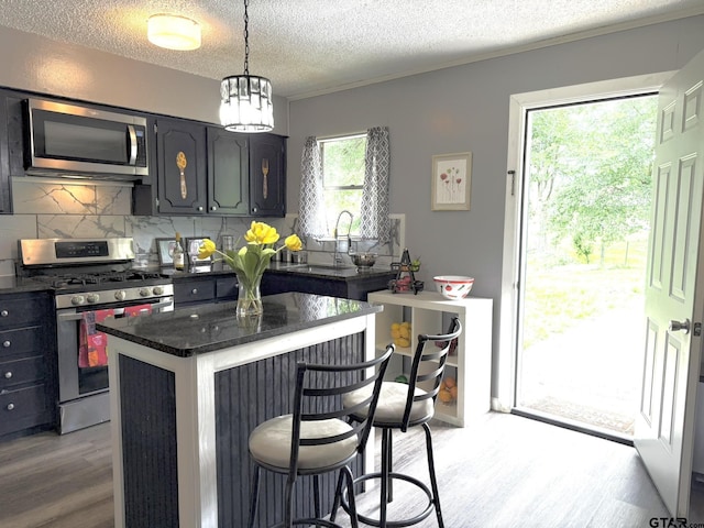 412 W 25th St, Tyler, TX 75702 - kitchen with stainless steel appliances, light wood-type flooring, a breakfast bar area, decorative backsplash, and a center island