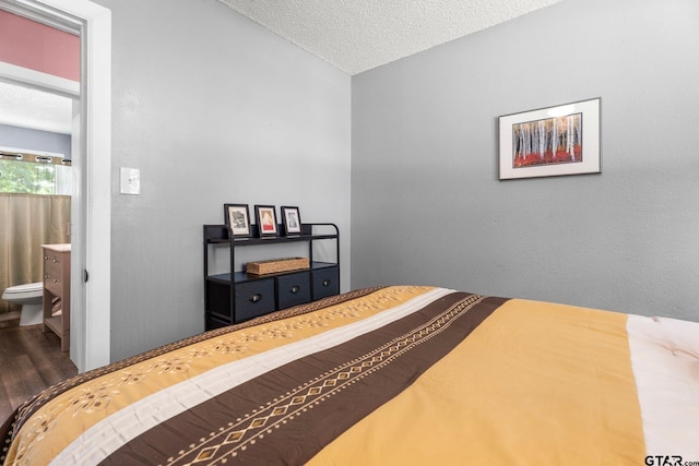 412 W 25th St, Tyler, TX 75702 - bedroom with wood finished floors, a textured ceiling, and connected bathroom
