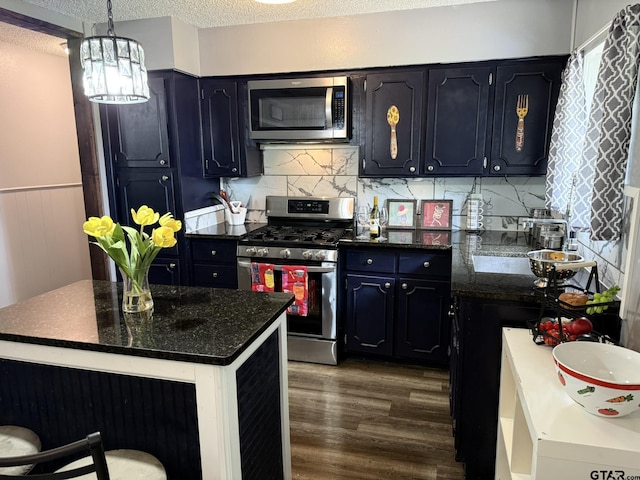 412 W 25th St, Tyler, TX 75702 - kitchen featuring appliances with stainless steel finishes, dark wood finished floors, a textured ceiling, decorative backsplash, and a chandelier