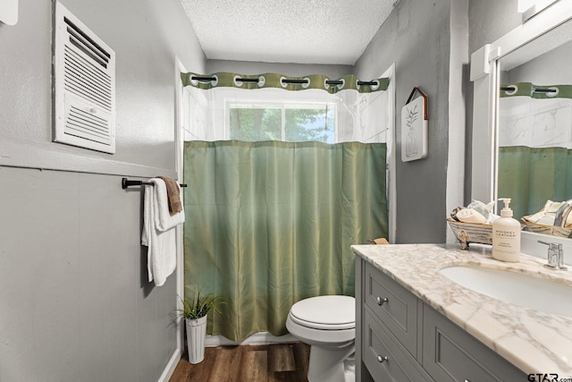 412 W 25th St, Tyler, TX 75702 - bathroom featuring a textured ceiling, vanity, wood finished floors, and a wainscoted wall