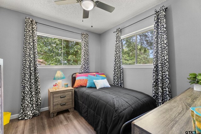 412 W 25th St, Tyler, TX 75702 - bedroom featuring wood finished floors, multiple windows, a textured ceiling, and ceiling fan
