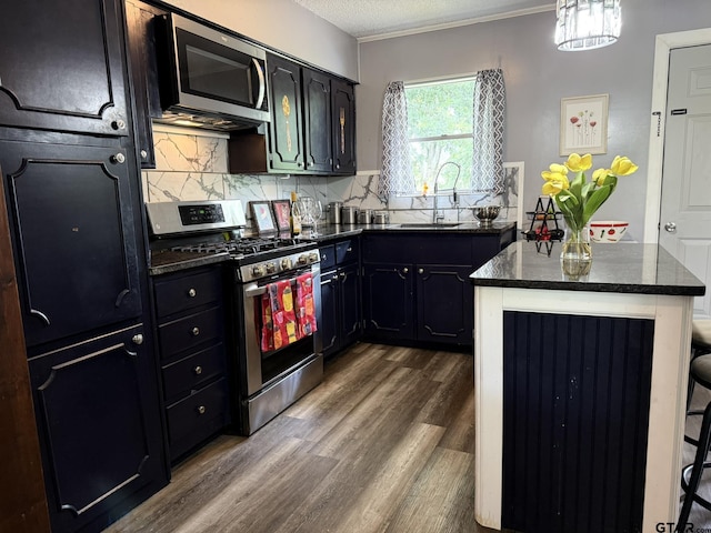 412 W 25th St, Tyler, TX 75702 - kitchen featuring appliances with stainless steel finishes, dark wood finished floors, decorative backsplash, a center island, and dark cabinetry