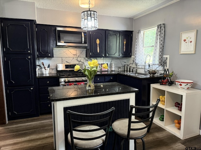 412 W 25th St, Tyler, TX 75702 - kitchen featuring stainless steel appliances, a textured ceiling, dark wood-style flooring, decorative backsplash, and a kitchen bar