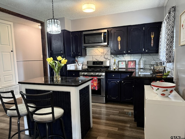 412 W 25th St, Tyler, TX 75702 - kitchen featuring stainless steel appliances, dark wood finished floors, dark countertops, tasteful backsplash, and a textured ceiling