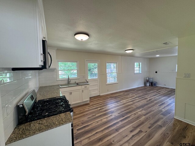 320 Northcrest Dr, Tyler, TX 75702 - kitchen with stainless steel appliances, dark wood-style floors, white cabinets, open floor plan, and backsplash