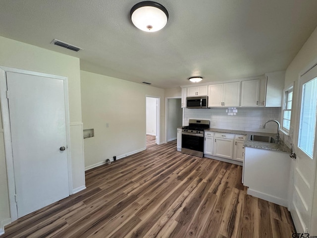 320 Northcrest Dr, Tyler, TX 75702 - kitchen with stainless steel appliances, dark wood-type flooring, white cabinetry, backsplash, and light countertops
