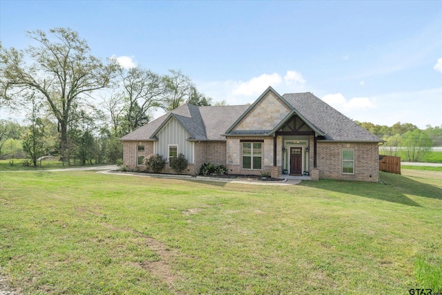 craftsman house with brick siding, a front yard, and a shingled roof