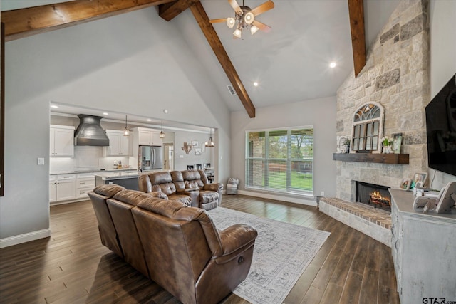 living area with high vaulted ceiling, beam ceiling, a ceiling fan, a stone fireplace, and dark wood finished floors