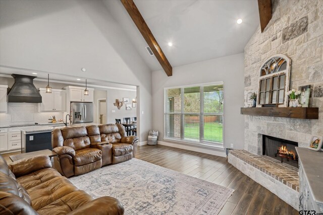 living area with high vaulted ceiling, a stone fireplace, dark wood-type flooring, and beamed ceiling