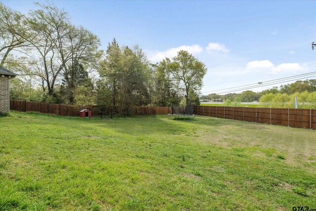 view of yard featuring a trampoline and a fenced backyard