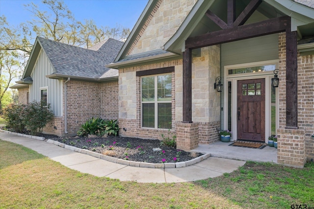 property entrance with a lawn, stone siding, brick siding, and roof with shingles