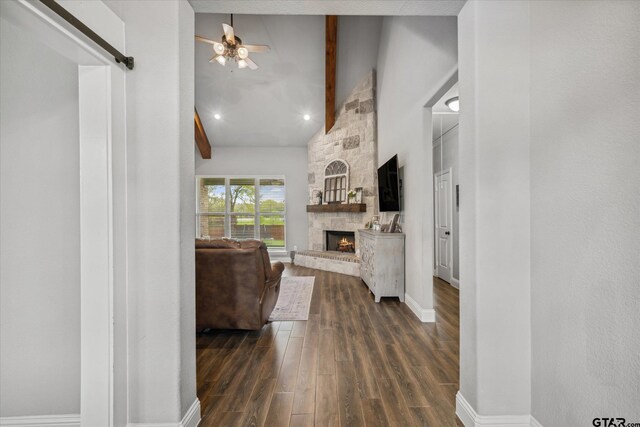 living area featuring dark wood-style flooring, baseboards, beam ceiling, a ceiling fan, and a fireplace