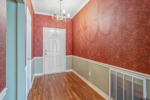 doorway with crown molding, hardwood / wood-style floors, and a chandelier