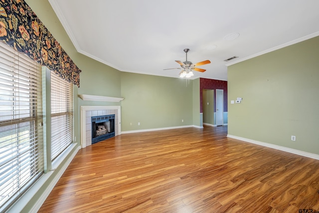 unfurnished living room with a tiled fireplace, ceiling fan, light hardwood / wood-style floors, and ornamental molding