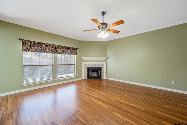 unfurnished living room featuring a tile fireplace, ceiling fan, hardwood / wood-style floors, and ornamental molding