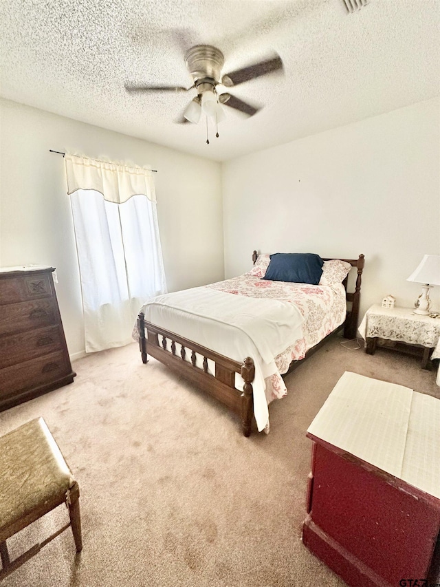 carpeted bedroom featuring a textured ceiling, ceiling fan, and visible vents