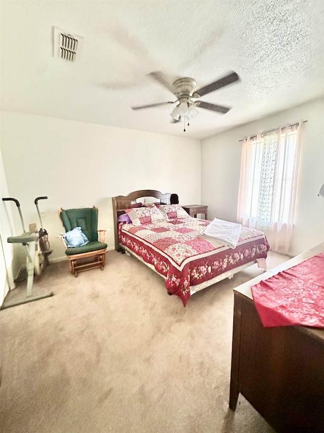 carpeted bedroom featuring visible vents, ceiling fan, and a textured ceiling