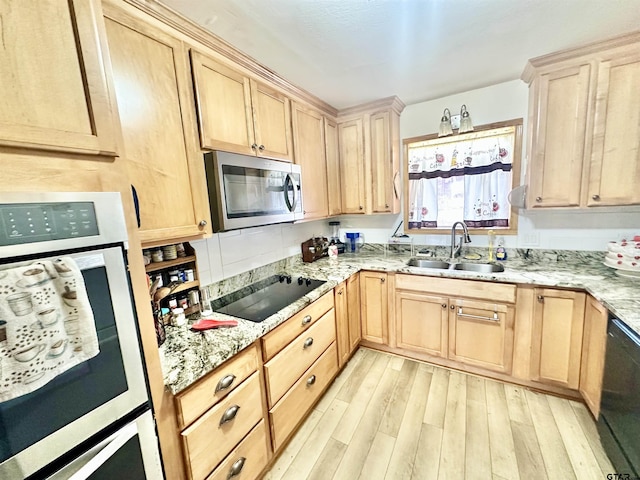 kitchen featuring light wood finished floors, black appliances, light brown cabinetry, and a sink