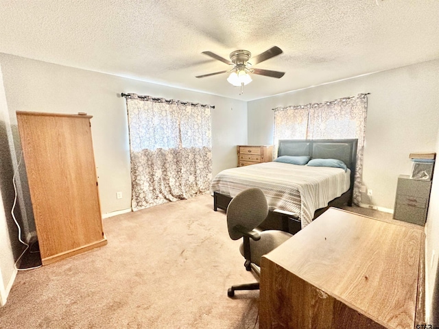 carpeted bedroom featuring a textured ceiling, a ceiling fan, and baseboards