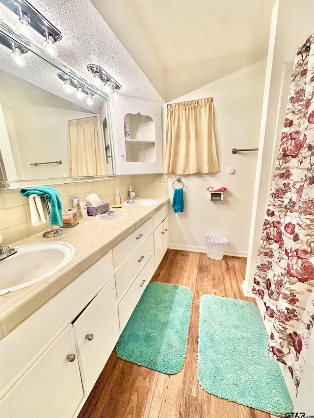 bathroom with tasteful backsplash, a textured ceiling, wood finished floors, and vanity