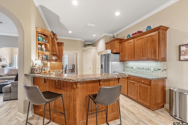 3109 Granbury Ct, Tyler, TX 75707 - kitchen featuring stainless steel fridge, crown molding, light wood-style floors, backsplash, and arched walkways