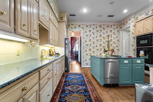 kitchen with ornamental molding, appliances with stainless steel finishes, light hardwood / wood-style floors, and sink