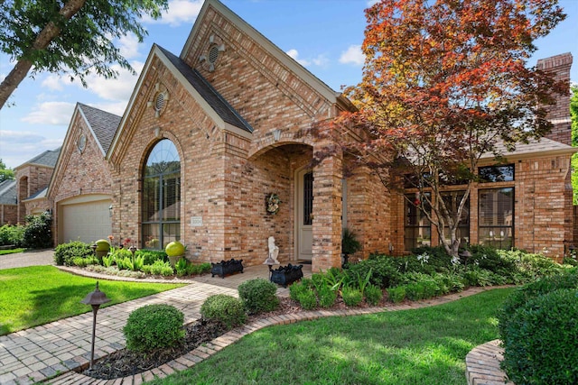 tudor-style house featuring a front lawn and a garage