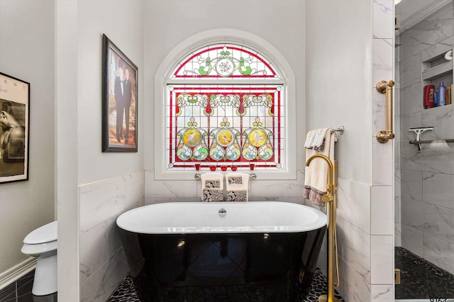 bathroom with tile walls, a bath, and toilet