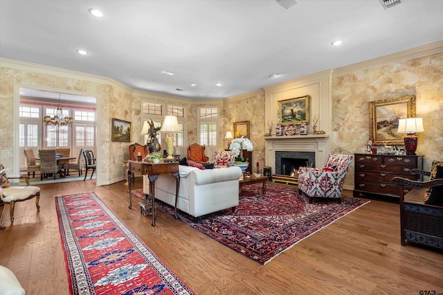 living room with hardwood / wood-style floors, crown molding, and an inviting chandelier