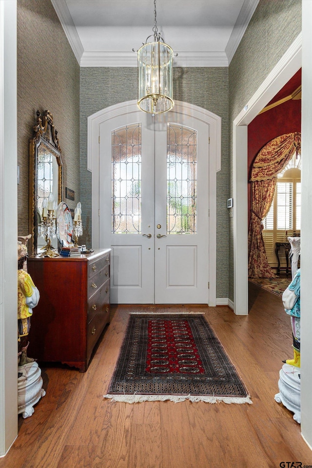 foyer featuring ornamental molding, french doors, a notable chandelier, and hardwood / wood-style flooring