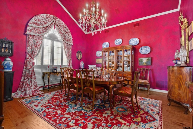 dining room with hardwood / wood-style flooring, vaulted ceiling, and a notable chandelier