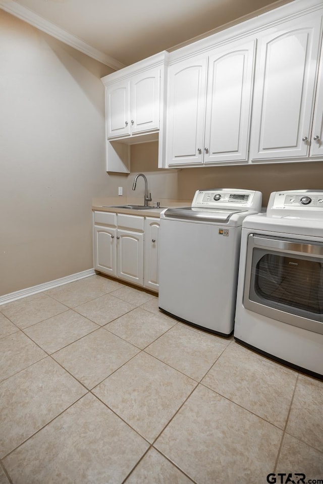 clothes washing area with cabinets, light tile patterned floors, crown molding, and washer and clothes dryer