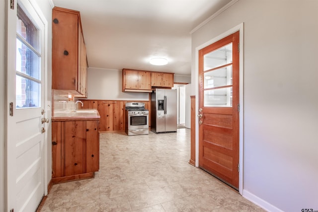 kitchen with stainless steel appliances, light countertops, crown molding, and a sink