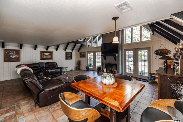 dining room with a textured ceiling, french doors, and lofted ceiling