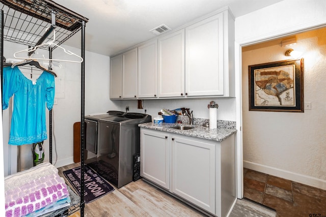 laundry area featuring washer and dryer, cabinets, sink, and light hardwood / wood-style floors