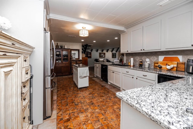 kitchen featuring white cabinetry, sink, stainless steel fridge, and light stone countertops