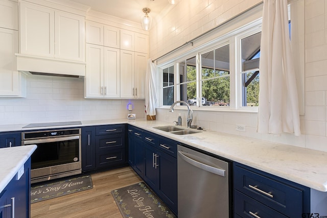 kitchen featuring white cabinetry, sink, stainless steel appliances, light hardwood / wood-style flooring, and decorative backsplash