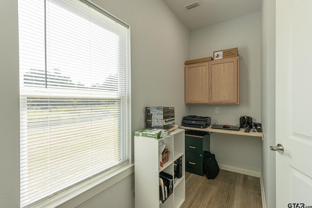 home office with light hardwood / wood-style floors and built in desk