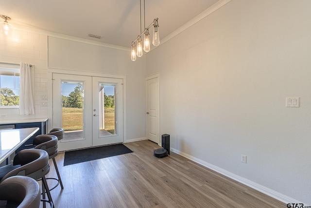 entryway with hardwood / wood-style flooring, ornamental molding, and french doors