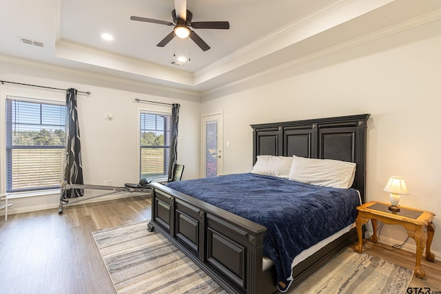 bedroom with a raised ceiling, ceiling fan, crown molding, and hardwood / wood-style flooring