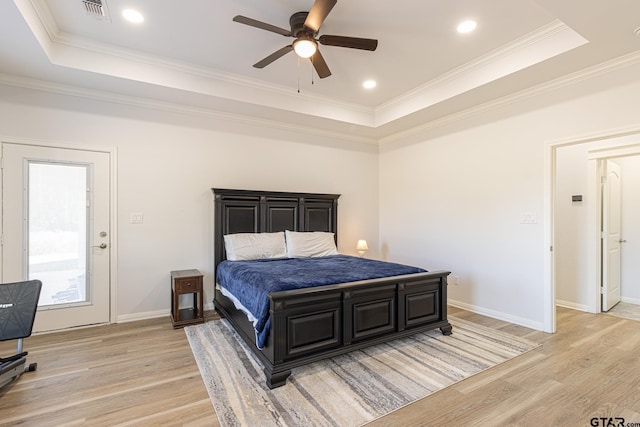 bedroom with a raised ceiling, light hardwood / wood-style flooring, and ornamental molding