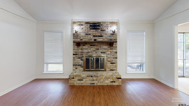 2505 Merry Ln, Tyler, TX 75701 - unfurnished living room featuring vaulted ceiling, wood finished floors, and a brick fireplace